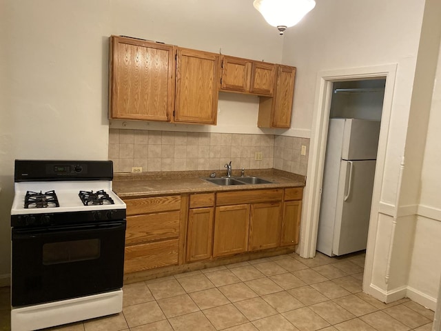 3320 W Monroe St, Chicago, IL 60624 - kitchen with range with gas stovetop, freestanding refrigerator, a sink, tasteful backsplash, and light tile patterned floors