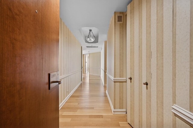 corridor with light wood-style floors and wallpapered walls