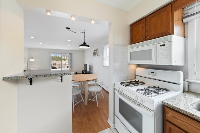 905 Graceland Ave Unit 12, Des Plaines, IL 60016 - kitchen with white appliances, brown cabinets, light wood-style flooring, a breakfast bar, and light stone counters