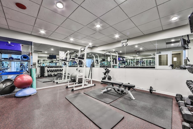 gym with a paneled ceiling and baseboards