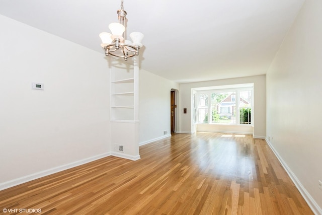 2852 W 84th Pl, Chicago, IL 60652 - unfurnished room with a chandelier, arched walkways, light wood-style flooring, and baseboards