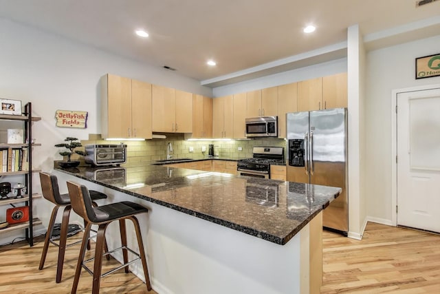 2251 W Saint Paul Ave Unit 2D, Chicago, IL 60647 - kitchen featuring stainless steel appliances, light brown cabinetry, a peninsula, dark stone counters, and recessed lighting