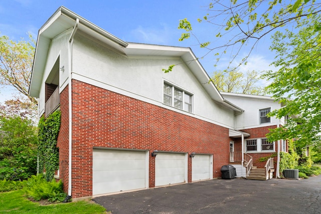 1040 Shermer Rd, Northbrook, IL 60062 - view of side of home featuring cooling unit, driveway, stucco siding, brick siding, and a garage