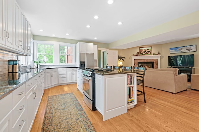 1040 Shermer Rd, Northbrook, IL 60062 - kitchen with appliances with stainless steel finishes, a kitchen breakfast bar, a fireplace, light wood-type flooring, and a kitchen island