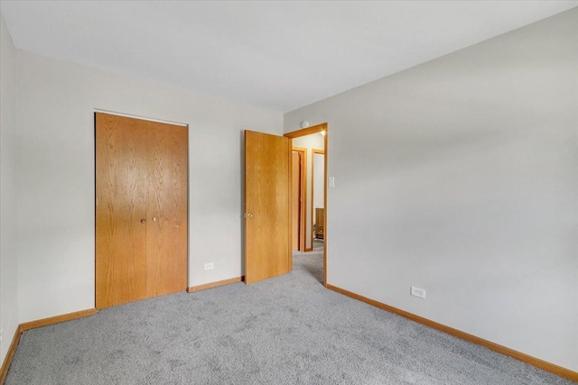 unfurnished bedroom featuring carpet flooring, baseboards, and a closet