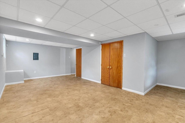 finished basement featuring a paneled ceiling, baseboards, and recessed lighting