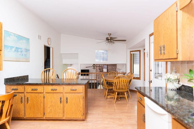 kitchen featuring white dishwasher, ceiling fan, a peninsula, light wood-type flooring, and dark stone counters