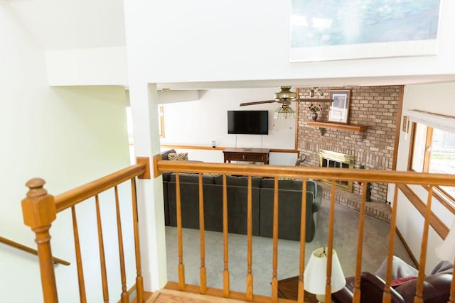 staircase with a brick fireplace and a ceiling fan