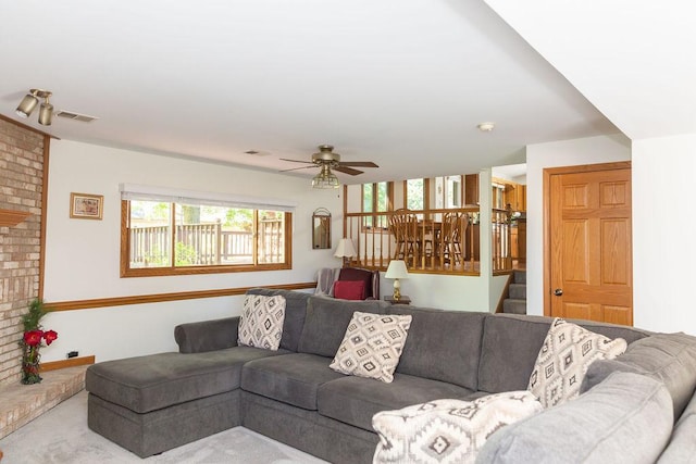 living area with ceiling fan, stairway, and carpet floors