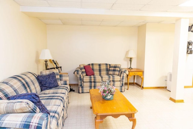 living area featuring tile patterned floors, baseboards, and a drop ceiling