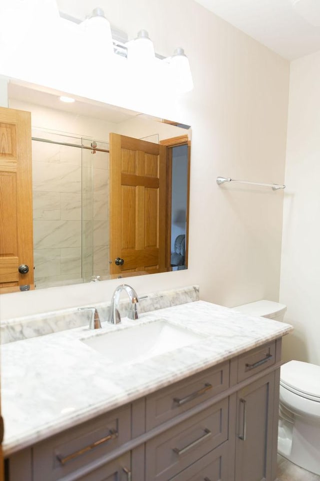 bathroom with toilet, vanity, and tiled shower