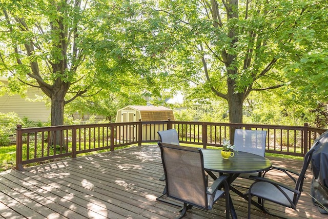 deck with a shed, outdoor dining area, and an outbuilding
