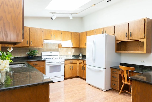 kitchen featuring white appliances, a sink, track lighting, under cabinet range hood, and backsplash