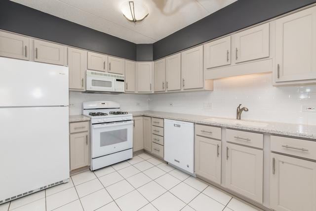 400 S NW Hwy Unit 309, Park Ridge, IL 60068 - kitchen with white appliances, a sink, light stone countertops, light tile patterned floors, and decorative backsplash