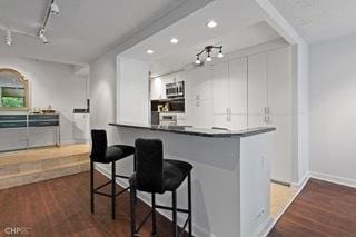 1430 N Astor St Unit 7A, Chicago, IL 60610 - kitchen featuring white cabinetry, track lighting, dark wood-style floors, a kitchen breakfast bar, and recessed lighting