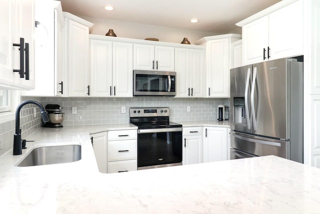 1811 Partridge Pt, Normal, IL 61761 - kitchen featuring appliances with stainless steel finishes, a sink, white cabinetry, backsplash, and light stone counters