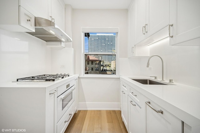 4300 N Marine Dr Unit 306, Chicago, IL 60613 - kitchen featuring under cabinet range hood, a sink, baseboards, light wood-style floors, and white oven
