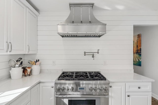 723 Beacon Dr, Lake Barrington, IL 60010 - kitchen featuring stainless steel range, extractor fan, white cabinetry, wood walls, and light stone countertops