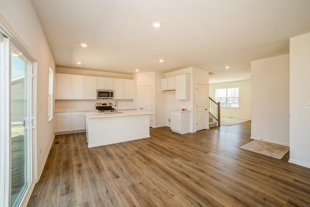 540 N Sycamore St, Hinckley, IL 60520 - kitchen with appliances with stainless steel finishes, white cabinets, a center island with sink, wood finished floors, and recessed lighting