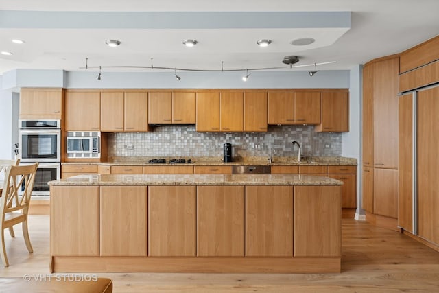40 E Cedar St Unit 8Cd, Chicago, IL 60611 - kitchen with stainless steel appliances, decorative backsplash, light wood-style flooring, light stone counters, and a kitchen island