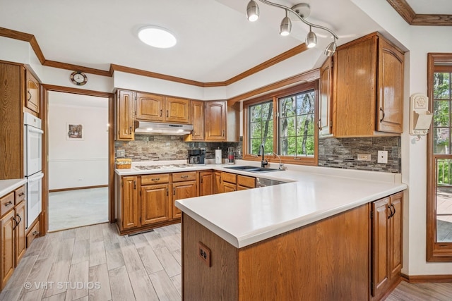 5808 Amherst Ct, Mchenry, IL 60050 - kitchen featuring a sink, under cabinet range hood, light countertops, crown molding, and brown cabinets