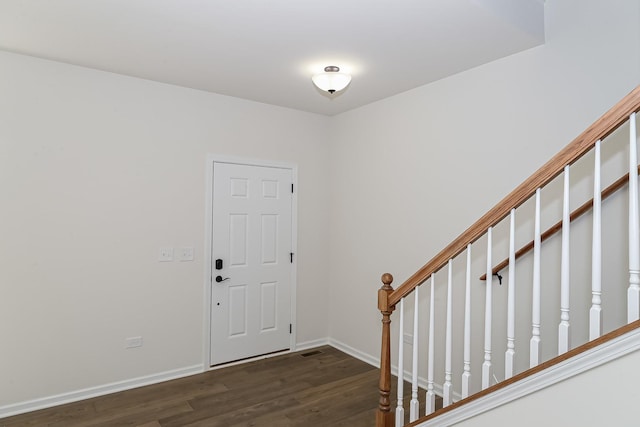 foyer entrance featuring dark wood-style floors, baseboards, and stairway