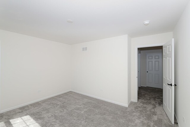 unfurnished room with light colored carpet and baseboards