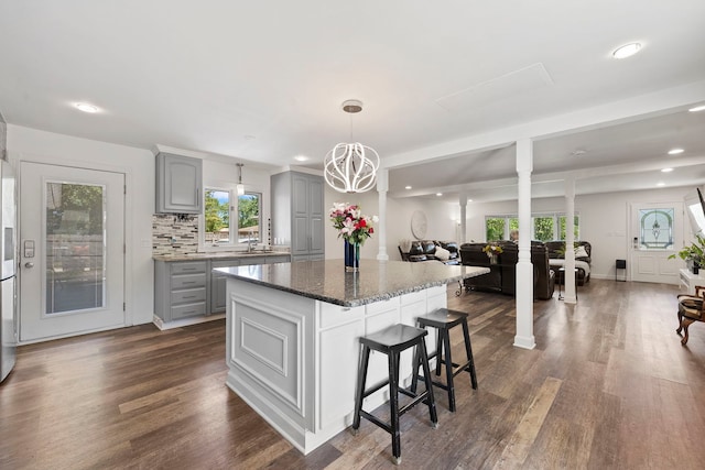 kitchen with gray cabinets, a sink, recessed lighting, a kitchen breakfast bar, and dark wood-style flooring