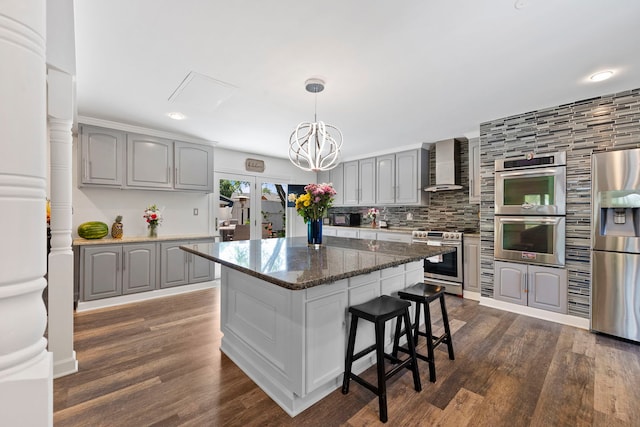 kitchen with appliances with stainless steel finishes, wall chimney exhaust hood, gray cabinets, dark wood-style floors, and recessed lighting