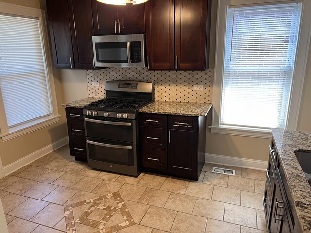 7949 S Manistee Ave, Chicago, IL 60617 - kitchen with stainless steel appliances, baseboards, backsplash, light stone counters, and dark brown cabinets