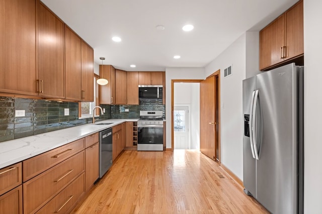 2934 Maple Ave, Berwyn, IL 60402 - kitchen featuring appliances with stainless steel finishes, light wood-style floors, tasteful backsplash, brown cabinets, and a sink