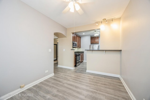 50 Forest Ave Unit 3S, Riverside, IL 60546 - unfurnished living room featuring ceiling fan, arched walkways, light wood-style floors, baseboards, and rail lighting