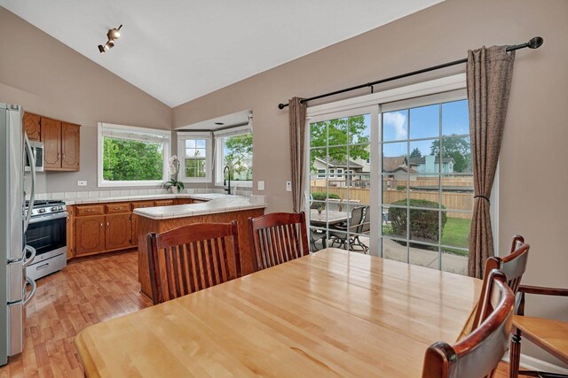 3513 Harris Dr, Joliet, IL 60431 - kitchen with appliances with stainless steel finishes, tile counters, light wood-style flooring, brown cabinetry, and lofted ceiling