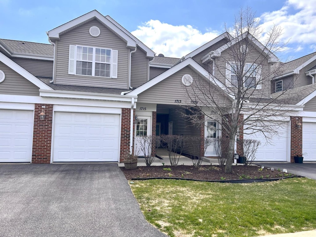 1715 White Oak Trl Unit C1, Cherry Valley, IL 61016 - view of front of house featuring brick siding, driveway, roof with shingles, and a garage