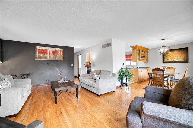 1016 W Willow Ln, Mount Prospect, IL 60056 - living room featuring a chandelier, light wood-type flooring, and an accent wall