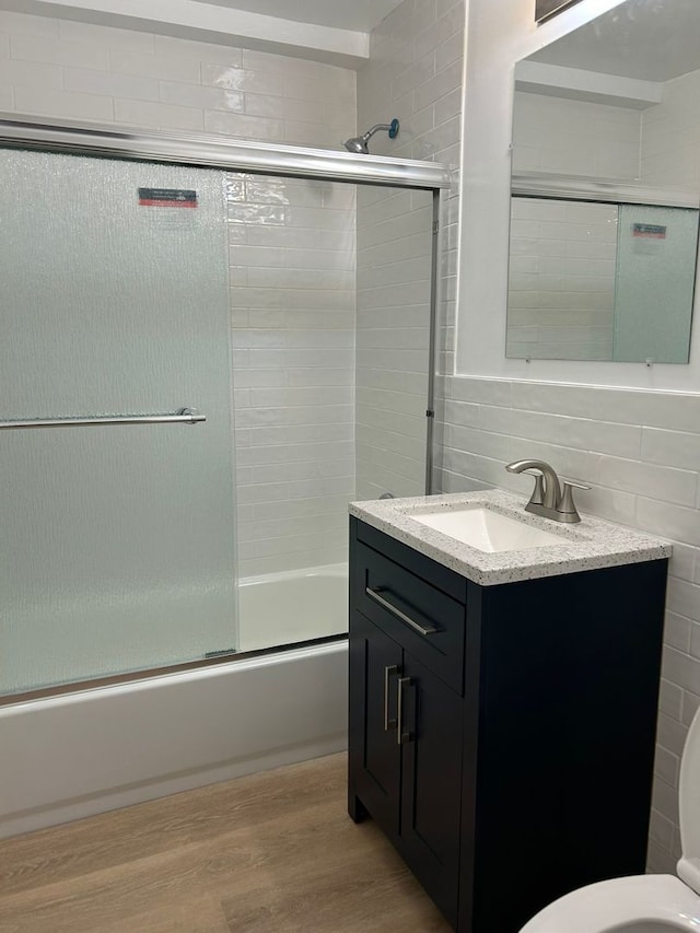 8521 Lotus Ave Unit 706, Skokie, IL 60077 - full bath featuring wood finished floors, bath / shower combo with glass door, vanity, toilet, and tile walls