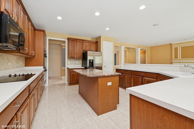 13881 Traverse Ct, Huntley, IL 60142 - kitchen with black appliances, a sink, a center island, decorative backsplash, and brown cabinets