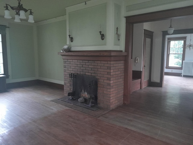 516 S Grant St, Earlville, IL 60518 - unfurnished living room with a chandelier, radiator heating unit, a brick fireplace, and wood finished floors