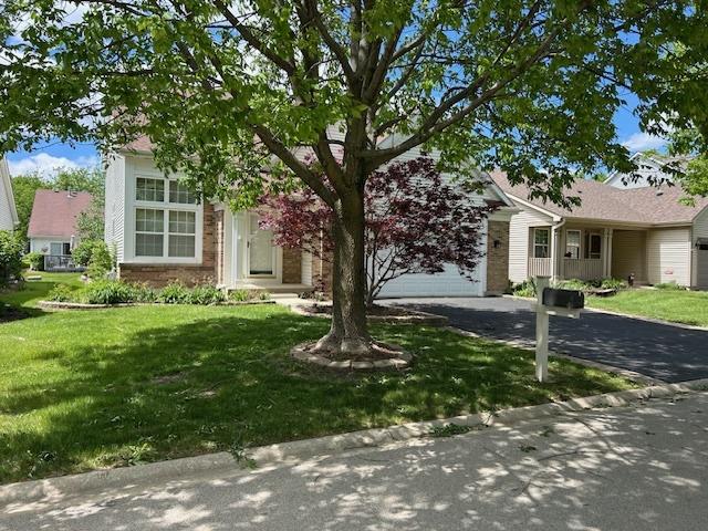 13804 Ironwood Dr, Plainfield, IL 60544 - view of property hidden behind natural elements featuring asphalt driveway, an attached garage, a front lawn, and brick siding