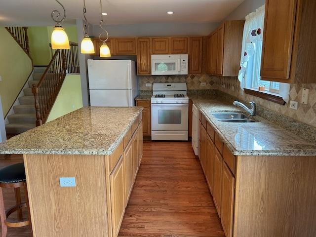 13804 Ironwood Dr, Plainfield, IL 60544 - kitchen with white appliances, a sink, light wood-type flooring, a kitchen bar, and tasteful backsplash