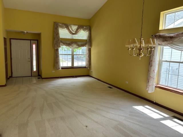 13804 Ironwood Dr, Plainfield, IL 60544 - unfurnished dining area with light colored carpet, a chandelier, and baseboards