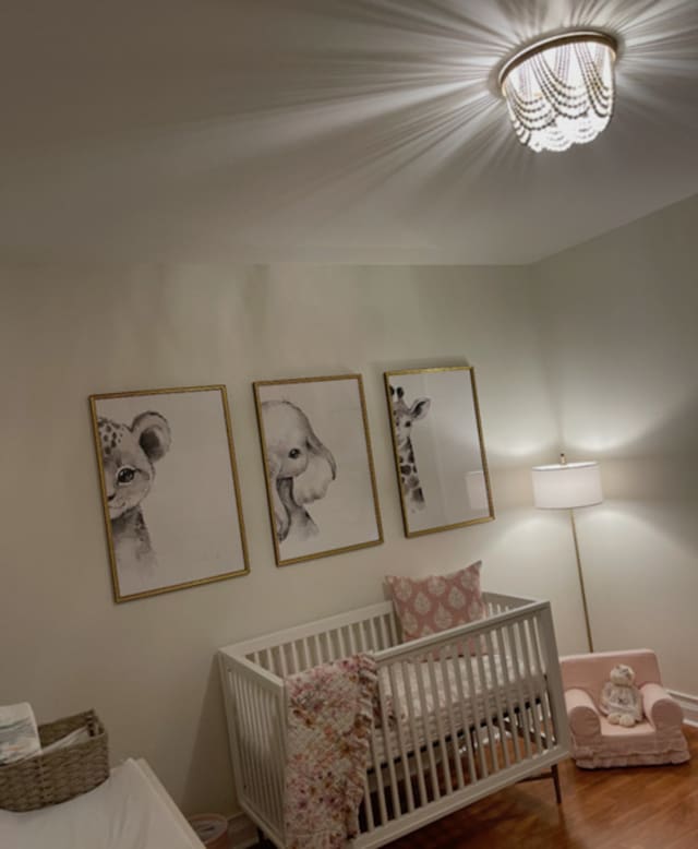 6643 W Belmont Ave Unit 1, Chicago, IL 60634 - bedroom with wood finished floors, a crib, and a chandelier