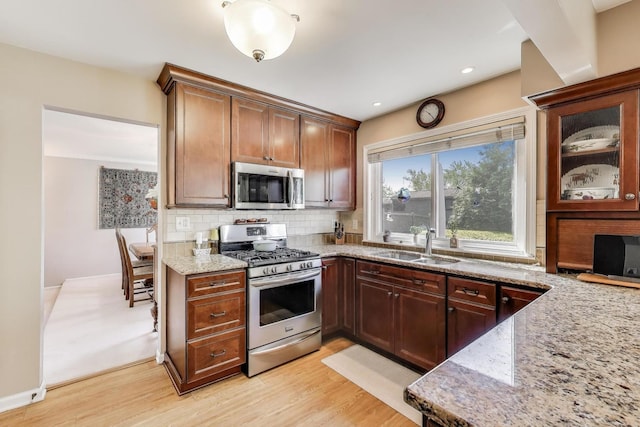 609 Bryce Trl, Roselle, IL 60172 - kitchen featuring appliances with stainless steel finishes, a sink, light stone countertops, decorative backsplash, and light wood-style flooring
