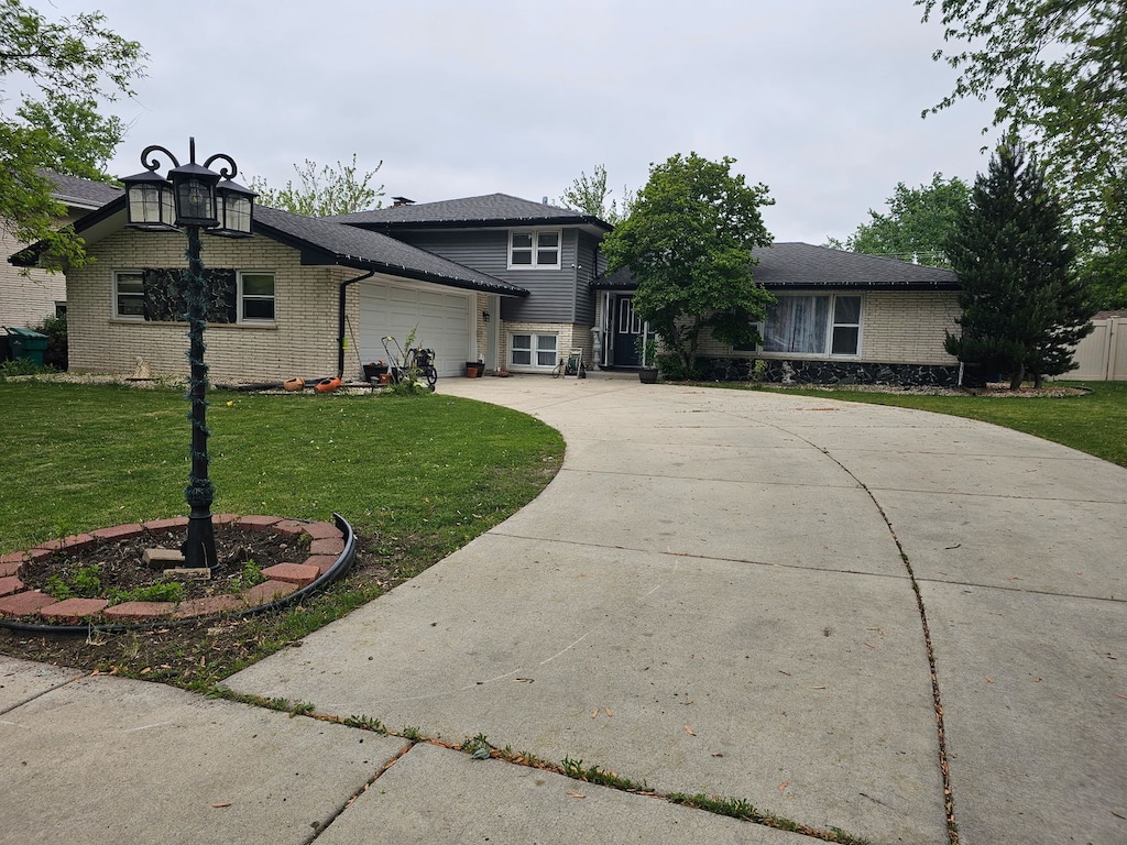 split level home with a garage, a front lawn, concrete driveway, and brick siding