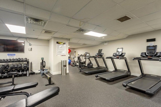 workout area featuring a drop ceiling and baseboards