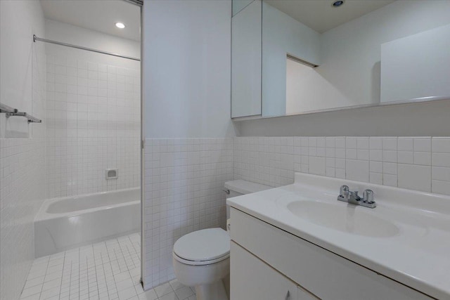 full bath with toilet, tile walls, tile patterned flooring, vanity, and tub / shower combination