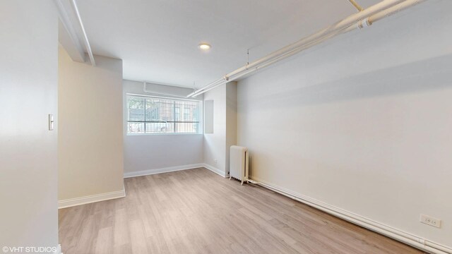 2636 W Grand Ave, Chicago, IL 60612 - empty room with radiator heating unit, wood finished floors, baseboards, and recessed lighting