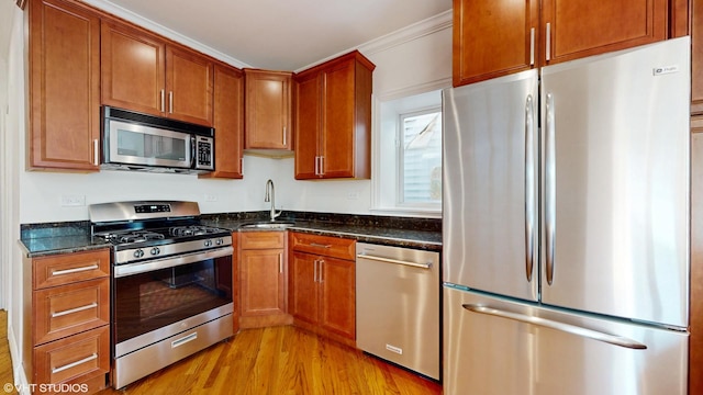 2636 W Grand Ave, Chicago, IL 60612 - kitchen with stainless steel appliances, a sink, light wood-style floors, dark stone countertops, and brown cabinetry