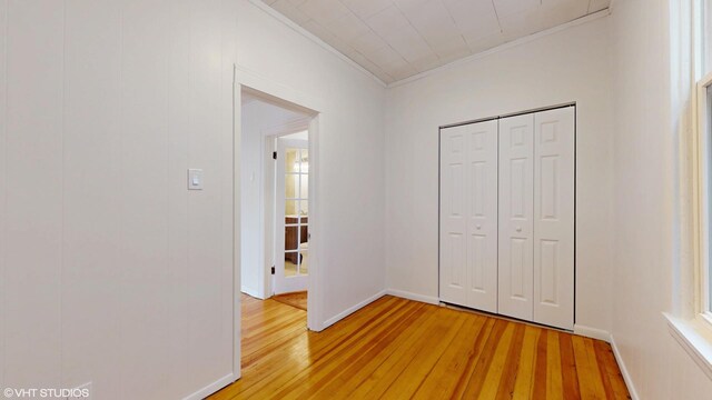 2636 W Grand Ave, Chicago, IL 60612 - unfurnished bedroom featuring light wood finished floors, ornamental molding, a closet, and baseboards
