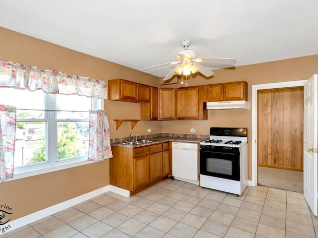 kitchen with gas range oven, dishwasher, under cabinet range hood, a sink, and baseboards